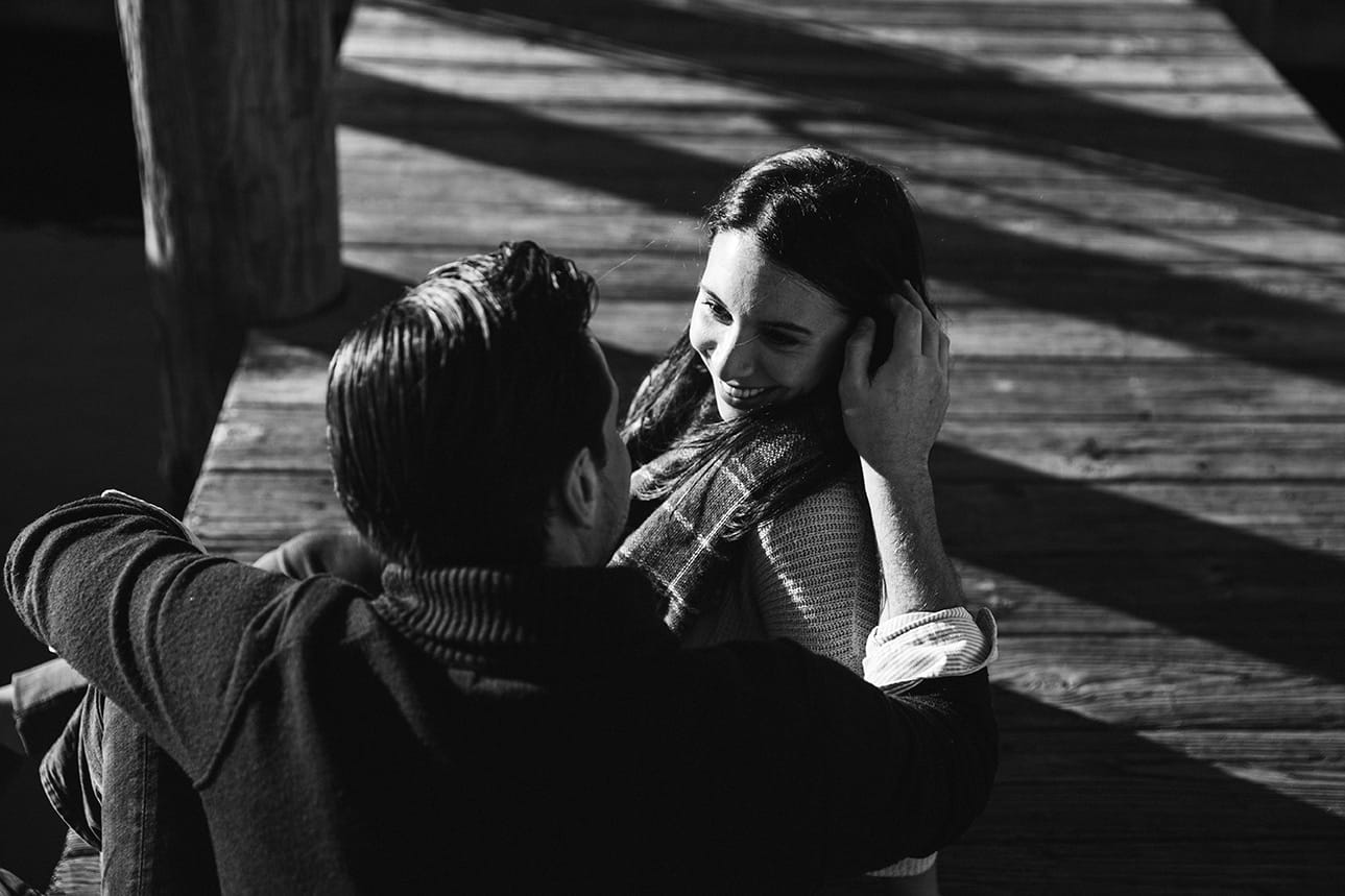 A documentary photograph of a couple sitting together on the dock during their honeymoon photo session on Martha's Vineyard