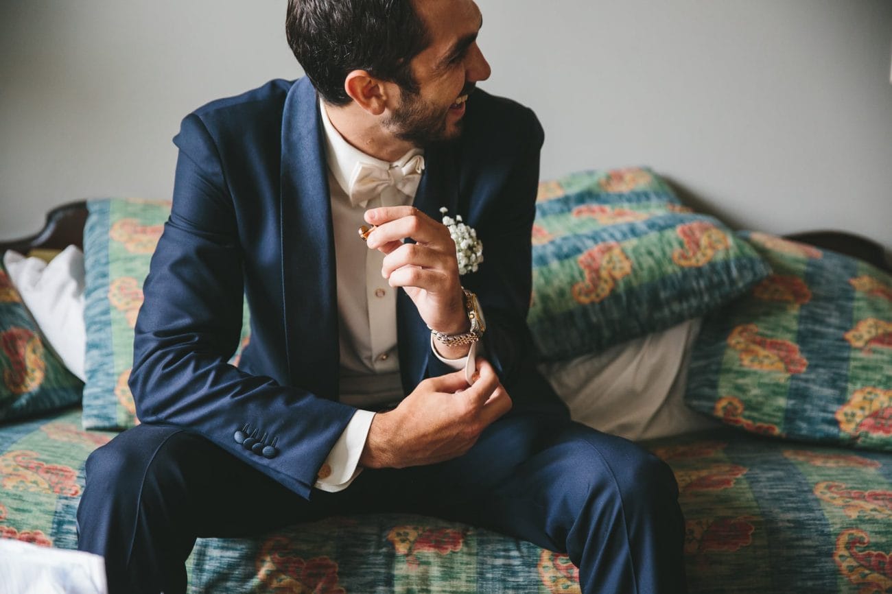 A documentary photograph of groom putting on cufflinks before his State Room Wedding in Boston, Massachusetts