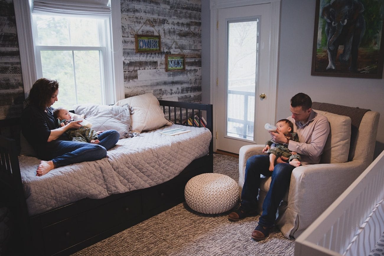 A documentary photograph of parents feeding their twin boys during an in home family session in Boston, Massachusetts