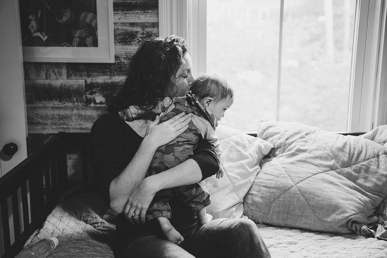 A documentary photograph of a mom hugging her baby boy during an in home family session in Boston, Massachusetts