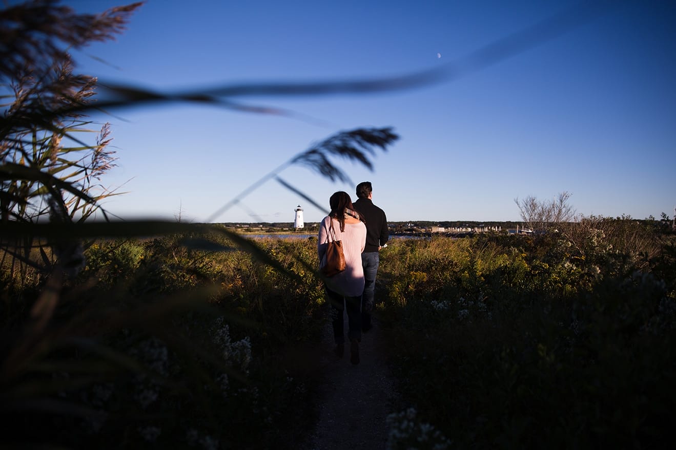 A documentary photograph of a couple walking to the lighthouse during their honeymoon photo session on Martha's Vineyard