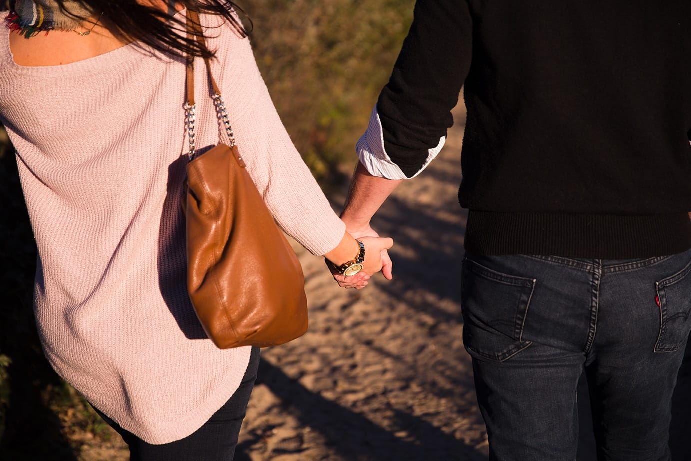 A documentary photograph of a couple holding hands as they walk on the beach during their honeymoon photo session on Martha's Vineyard
