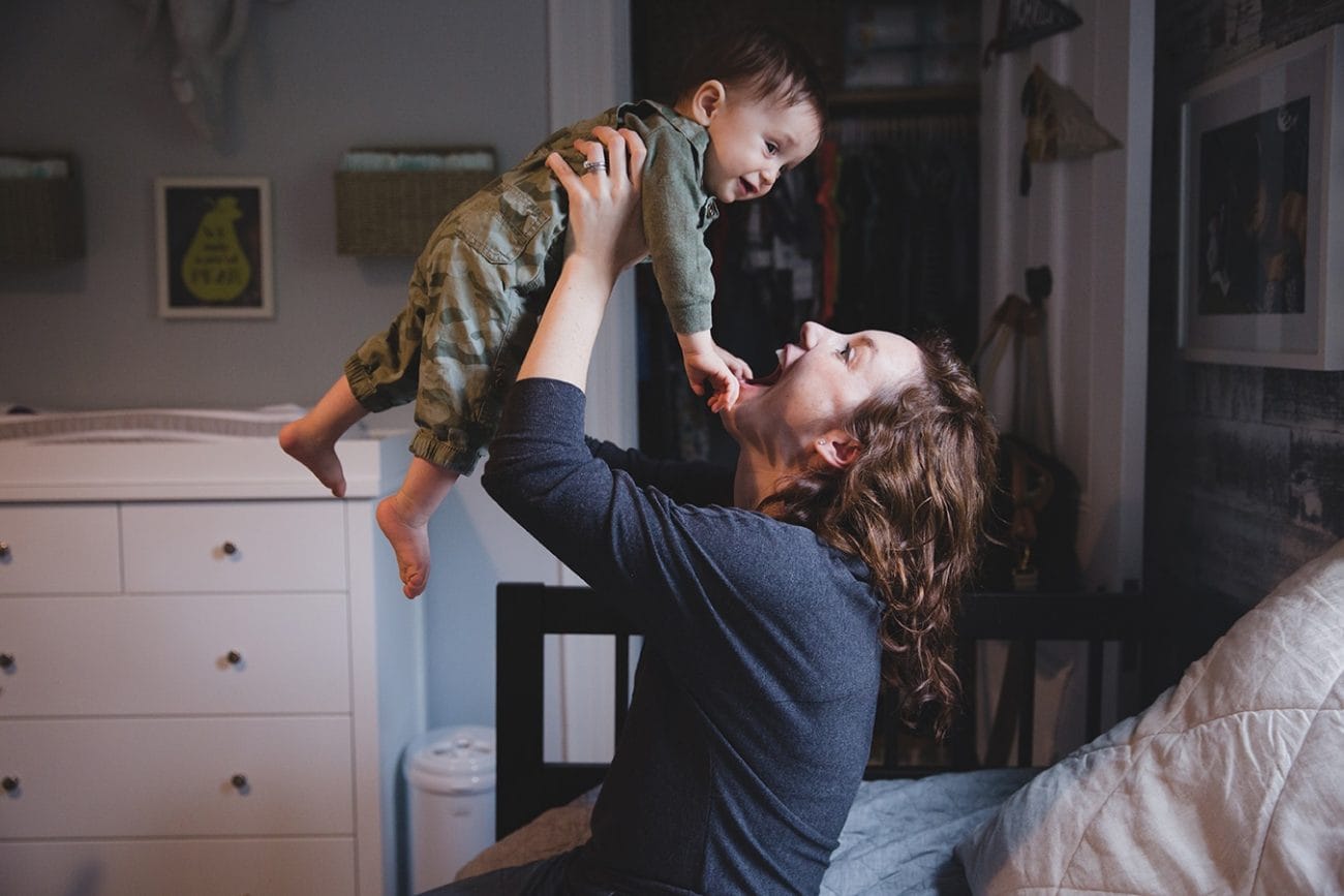 A documentary photograph of a mom playing with her baby boy during an in home family session in Boston, Massachusetts