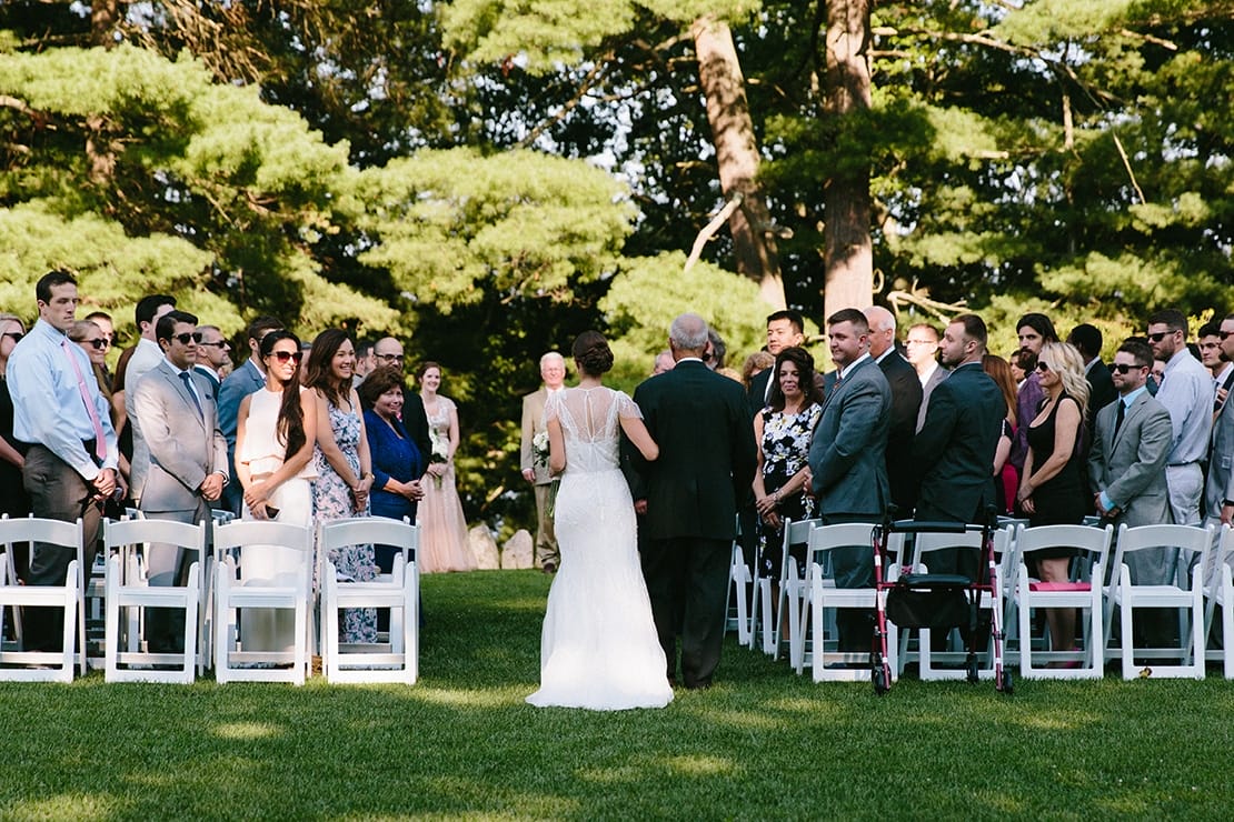 A documentary photograph of a bride walking up the aisle with her father during her Moraine Farm Wedding in Beverly, Massachusetts