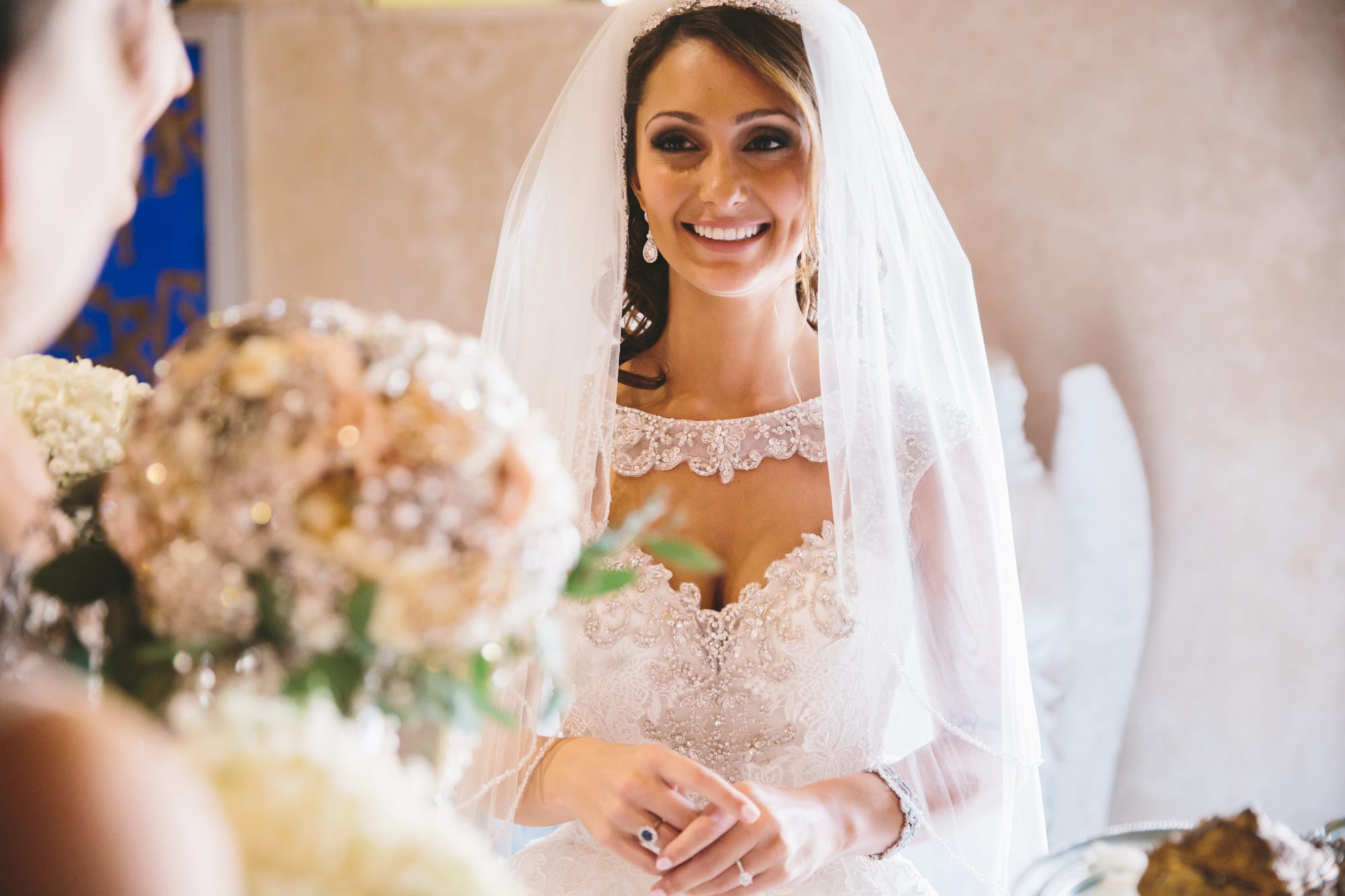 A documentary photograph of a bride smiling with her bridesmaids moments before she walks down the aisle of the Cathedral of the Holy Cross during her State Room Wedding