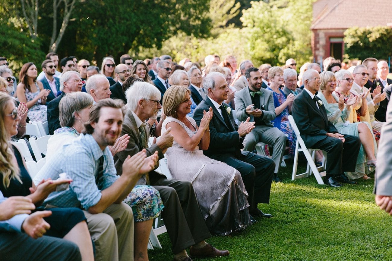 A documentary photograph of guests clapping during the a Moraine Farm Wedding ceremony in Beverly, Massachusetts