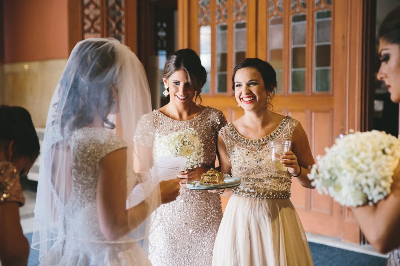 A documentary photograph of bridesmaids smiling moments before they walk down of the aisle of Cathedral of the Holy Cross during a State Room Wedding in Boston, Massachusetts