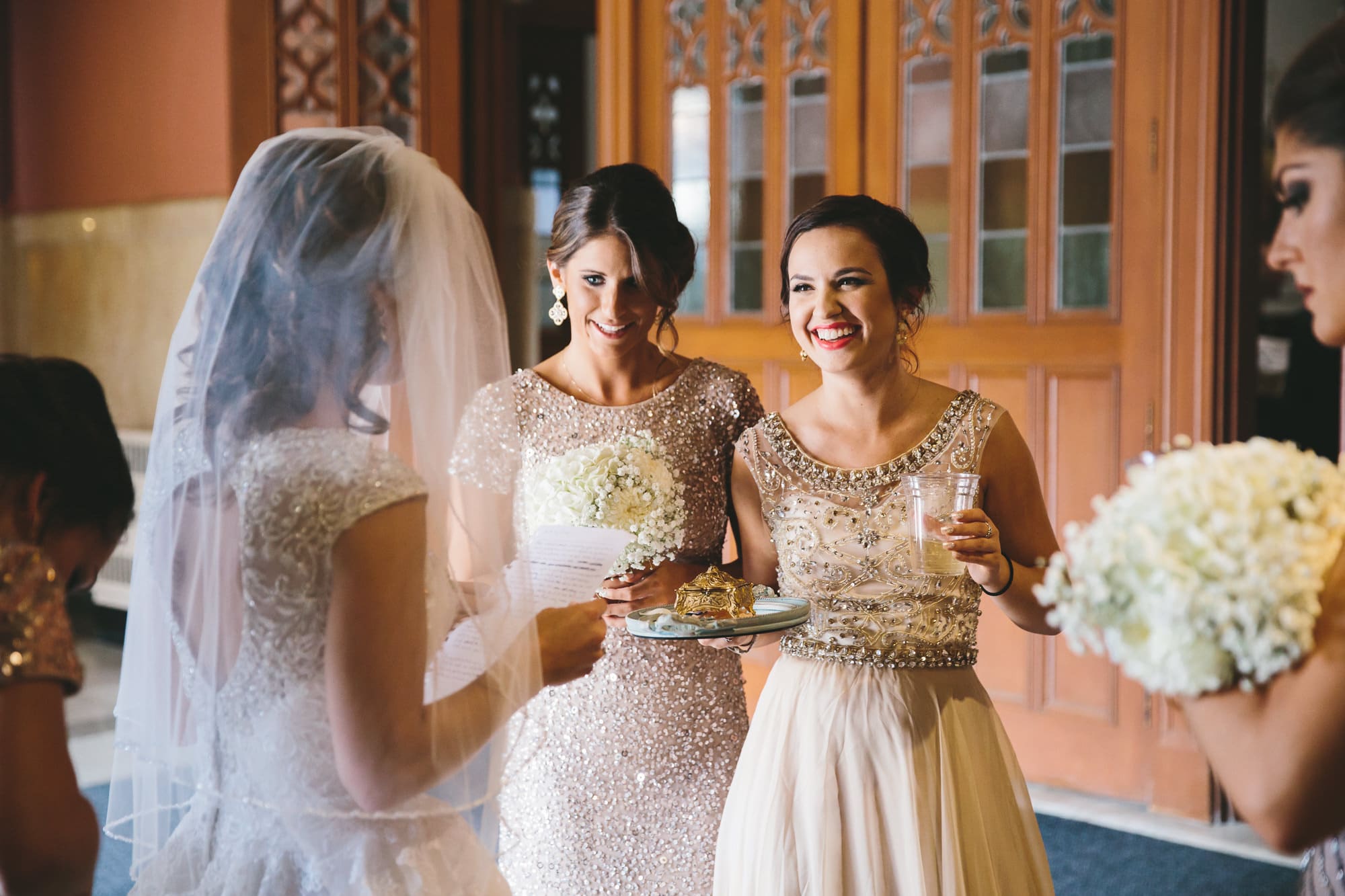 A documentary photograph of bridesmaids smiling moments before they walk down of the aisle of Cathedral of the Holy Cross during a State Room Wedding in Boston, Massachusetts