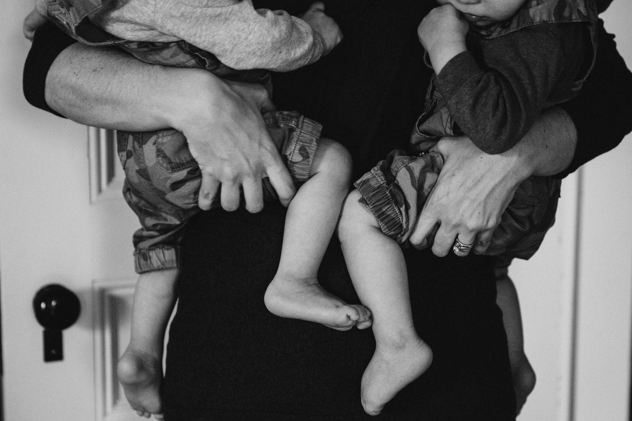 A documentary photograph of a mom holding her twin boys during an in home family session in Boston, Massachusetts