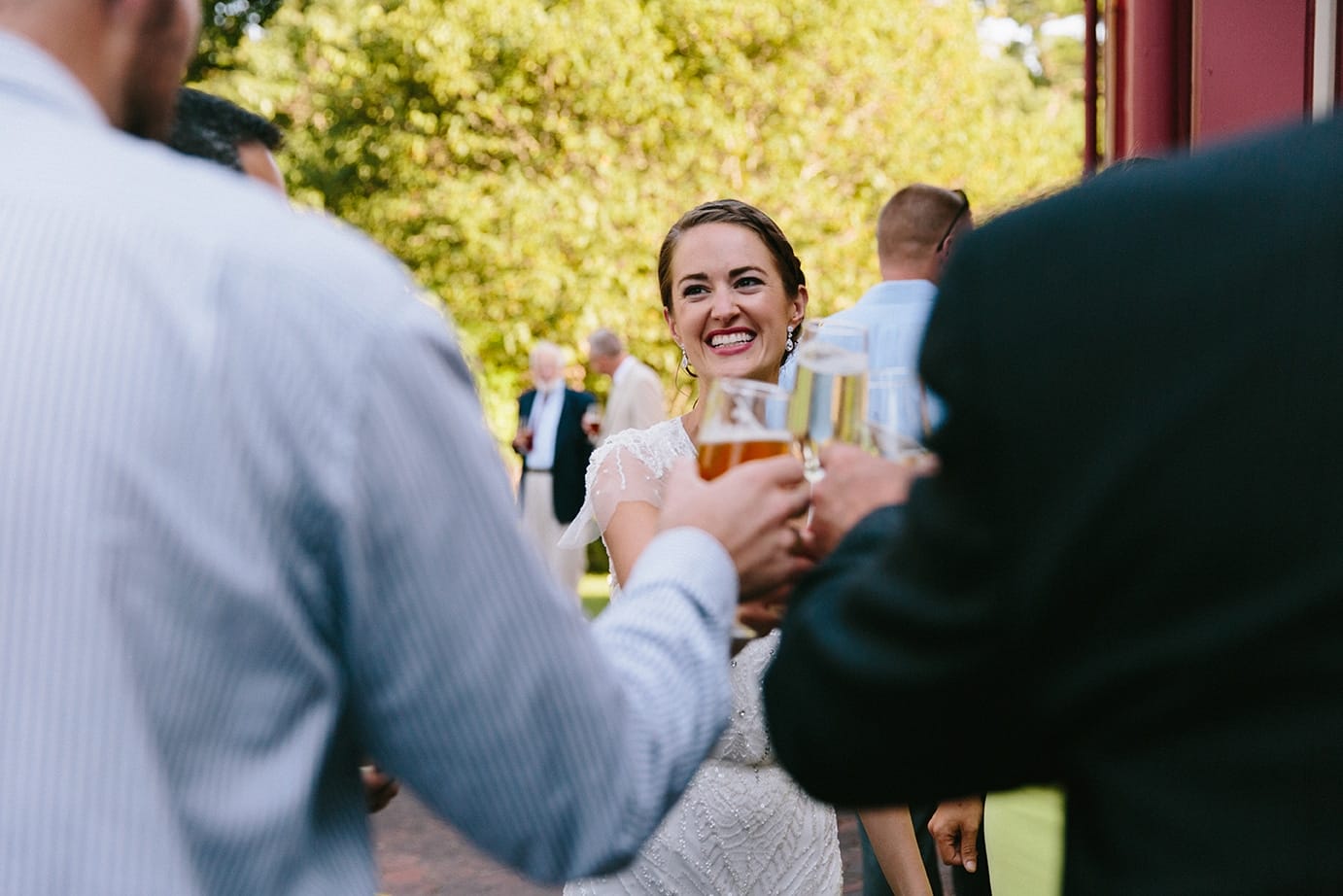 A documentary photograph of a bride celebrating with guests during her Moraine Farm Wedding in Beverly, Massachusetts