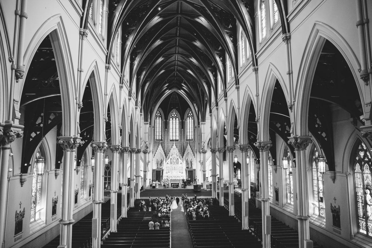 A documentary photograph of a bride walking down the aisle at the Cathedral of the Holy Cross during her State Room Wedding in Boston, Massachusetts