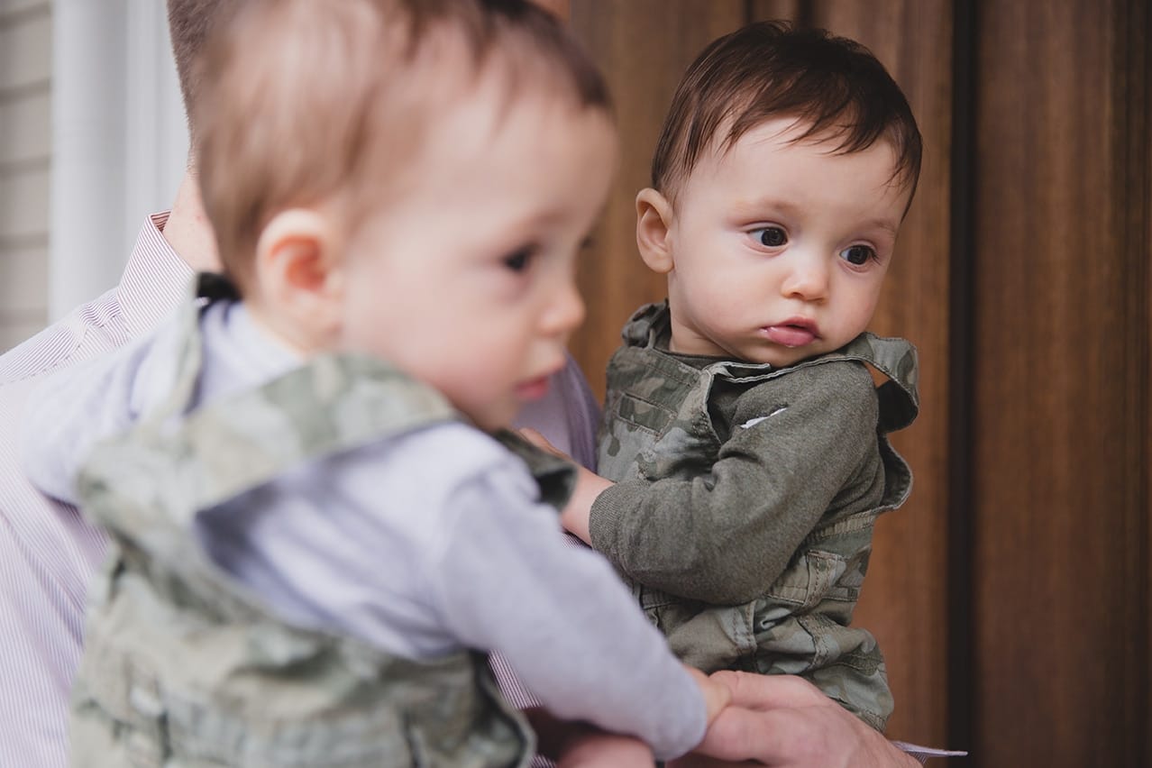A lifestyle portrait of twin boys being held by their father during an in home family session in Boston, Massachusetts