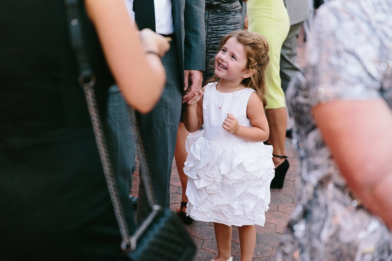 A documentary photograph of a flower girl amongst guests during a Moraine Farm Wedding in Beverly, Massachusetts