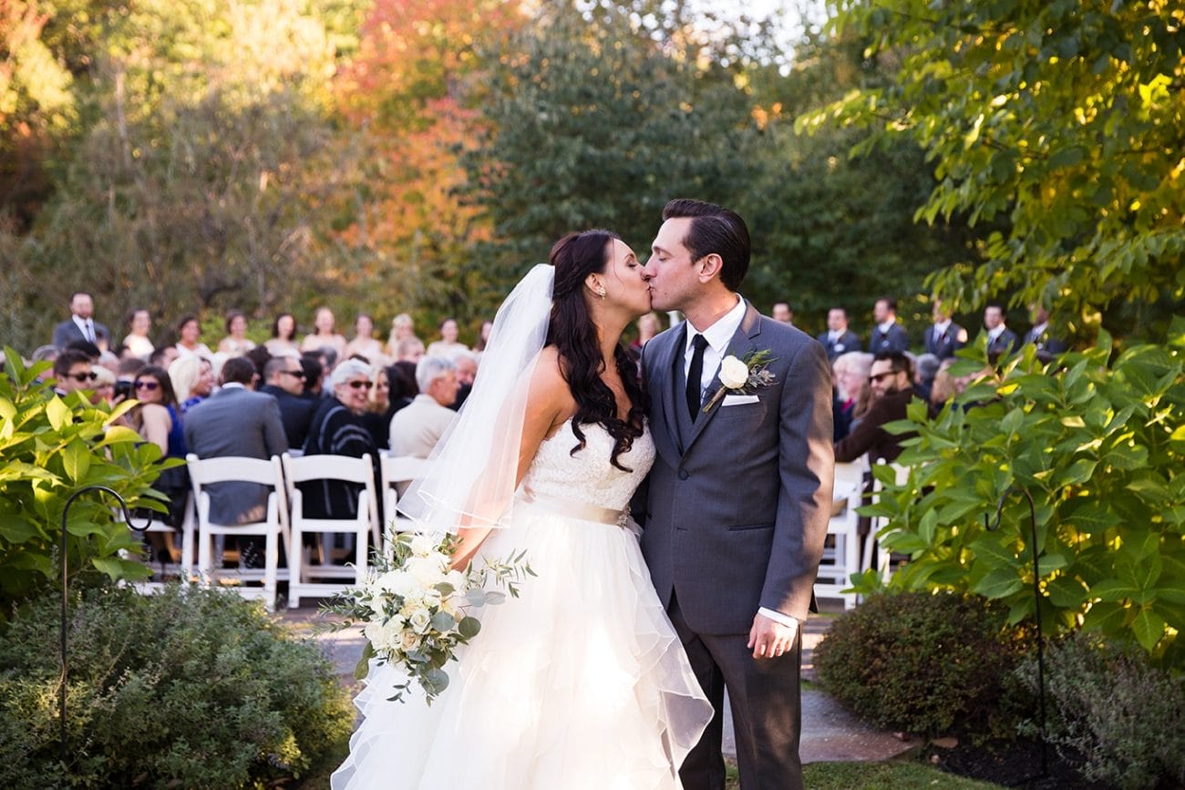 A documentary photograph of a bride and groom kissing after they walked down the aisle at their Harrington Farm Wedding in Princeton, Massachusetts 