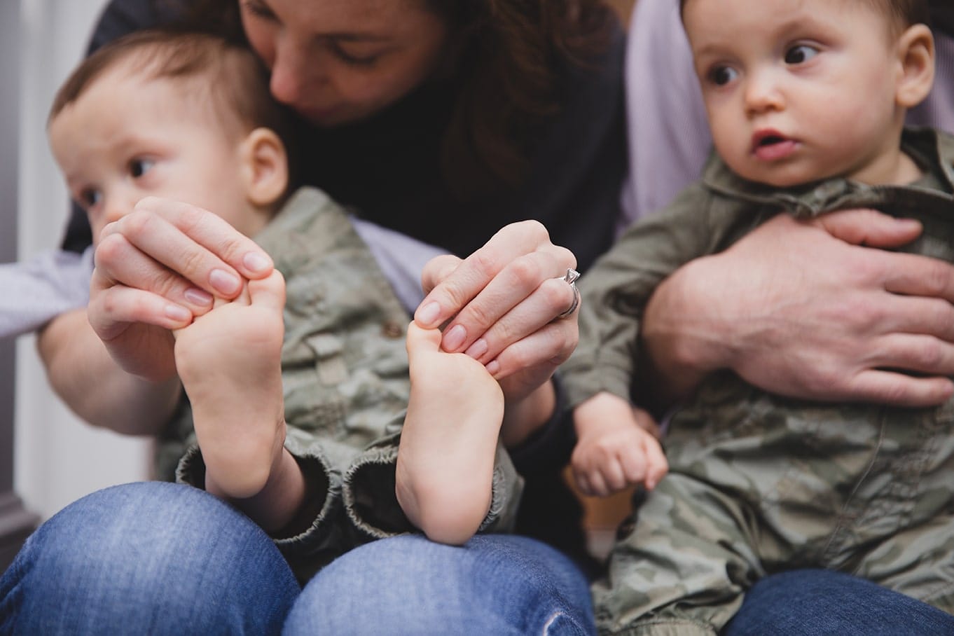 A documentary photograph of a mom playing with her sons toes during an in home family session in Boston, Massachusetts