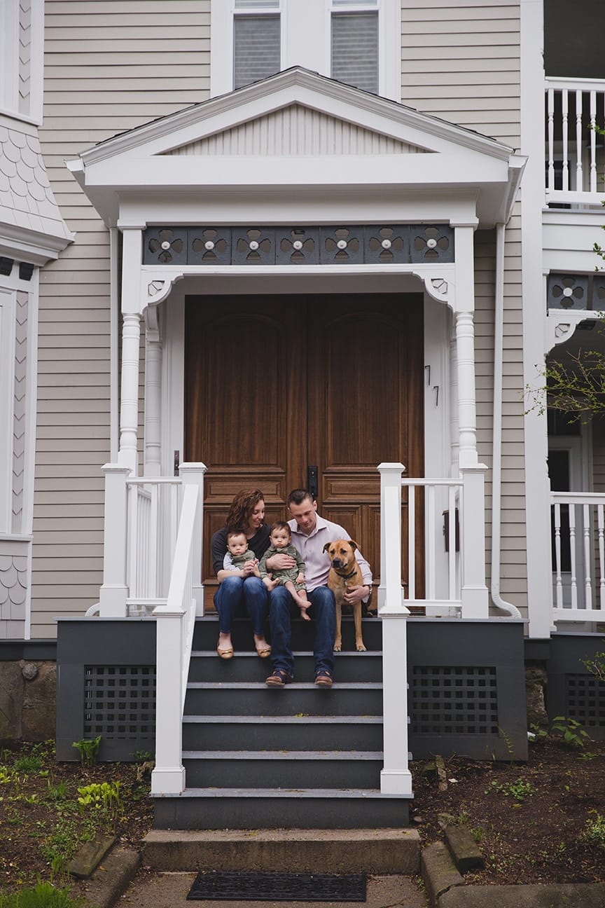A documentary photograph of a family sitting together on their front porch during an in home family session in Boston, Massachusetts 