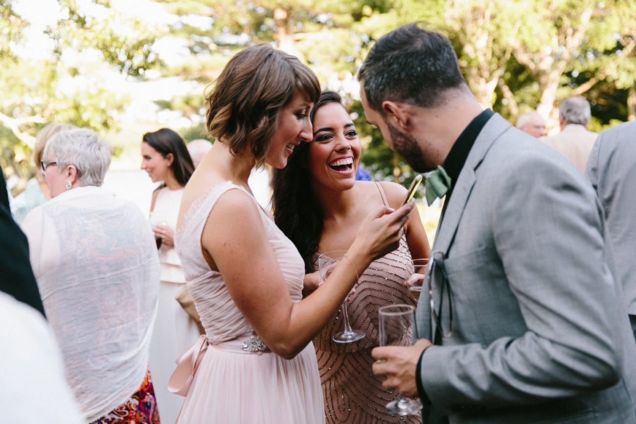 A documentary photograph of guests talking and laughing during a Moraine Farm Wedding in Beverly, Massachusetts