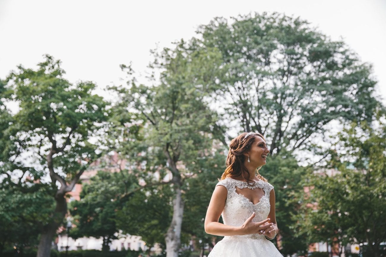 A documentary portrait of a bride laughing at the Boston Public Gardens during her State Room Wedding