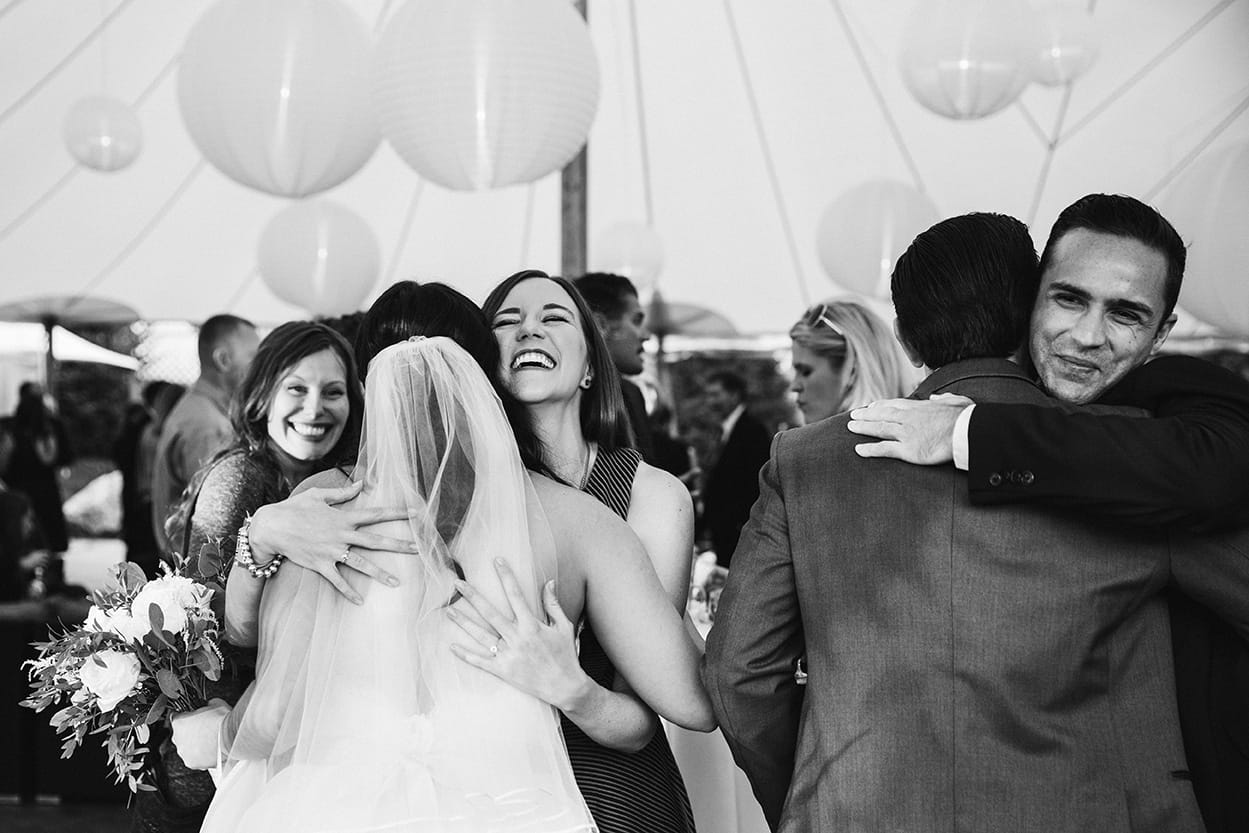 A documentary photograph of a bride and groom hugging their guests at a Harrington Farm Wedding in Princeton, Massachusetts