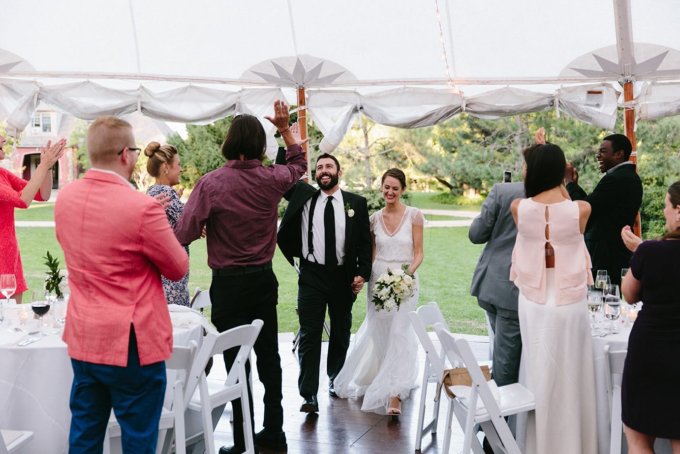 A documentary photograph of a bride and groom entering the reception tent at a Moraine Farm Wedding in Beverly, Massachusetts
