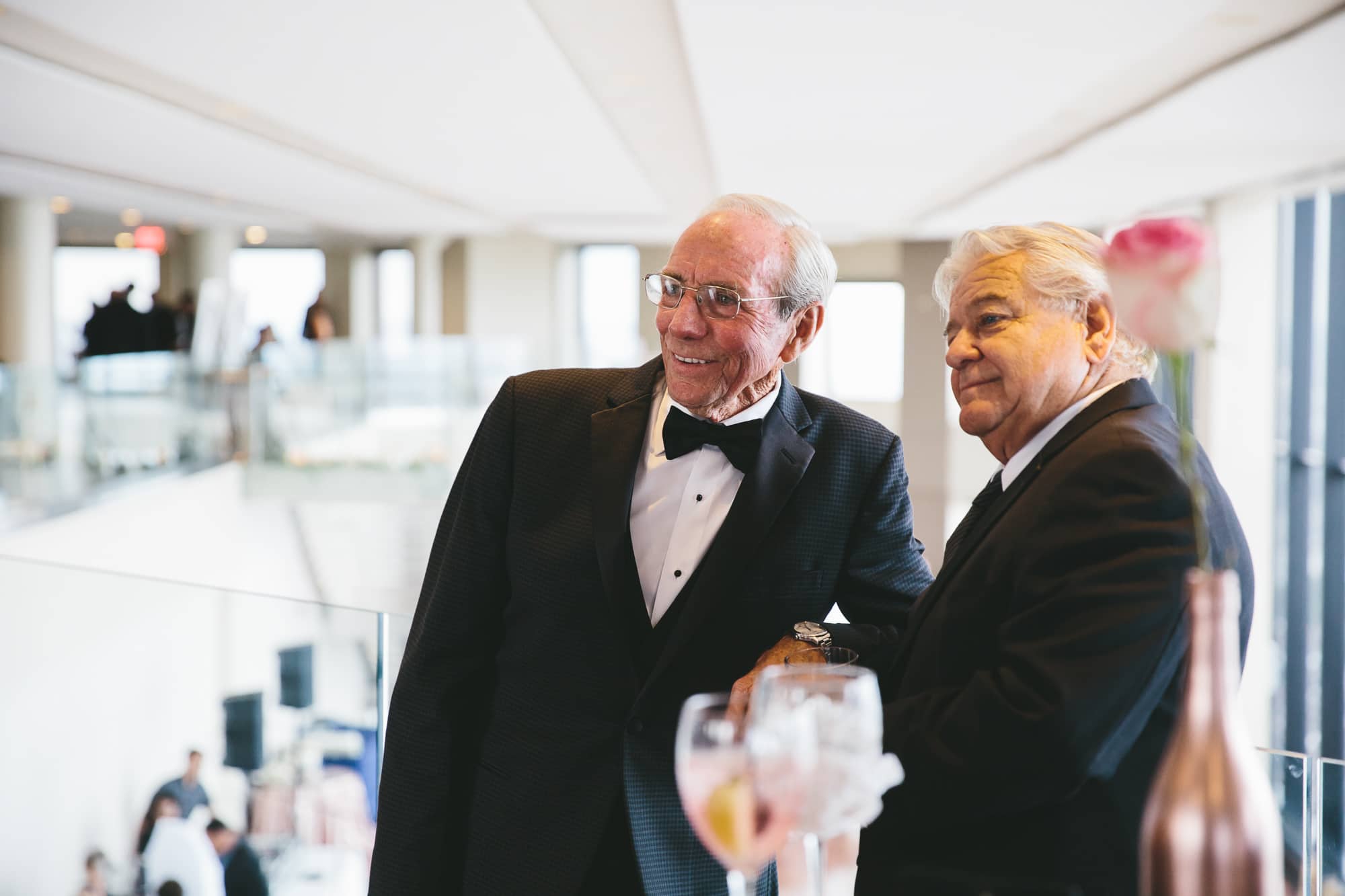 A documentary photograph of wedding guests smiling at the bride and groom during the cocktail hour of a State Room Wedding in Boston, Massachusetts