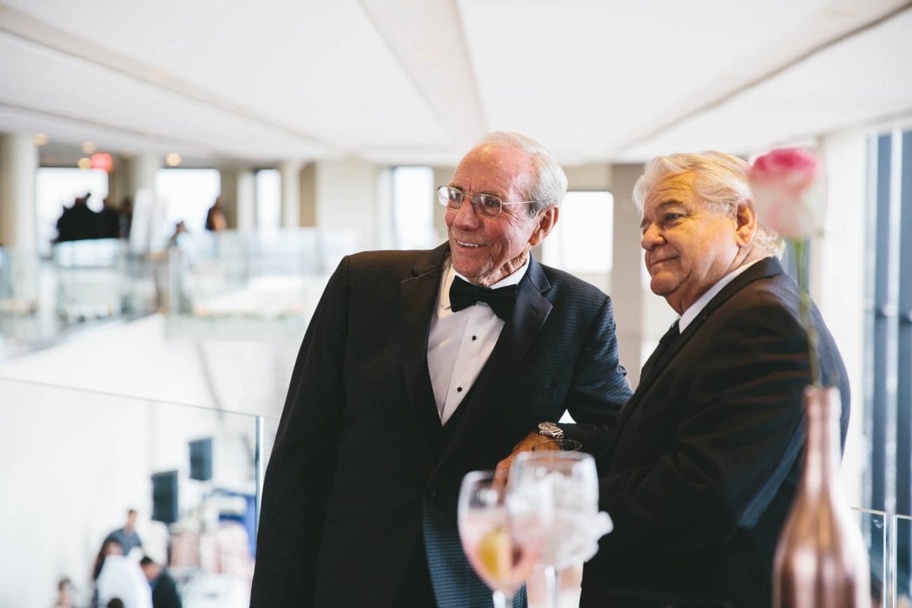 A documentary photograph of wedding guests smiling at the bride and groom during the cocktail hour of a State Room Wedding in Boston, Massachusetts
