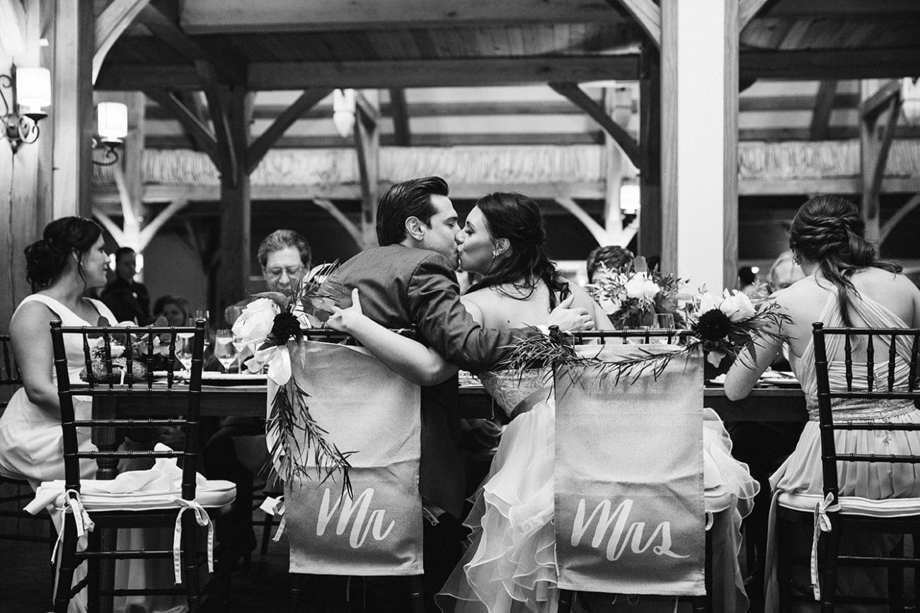 A documentary photograph of a bride ad groom sharing a kiss during dinner at their Harrington Farm Wedding in Princeton, Massachusetts
