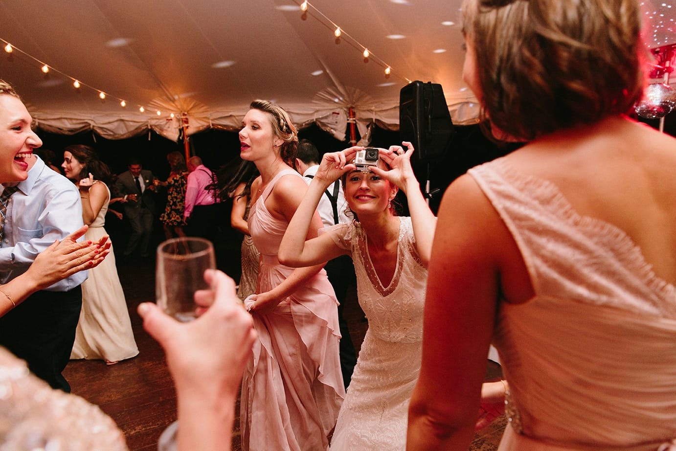 A documentary photograph of a bride dancing with a go pro camera during her Moraine Farm Wedding in Beverly, Massachusetts