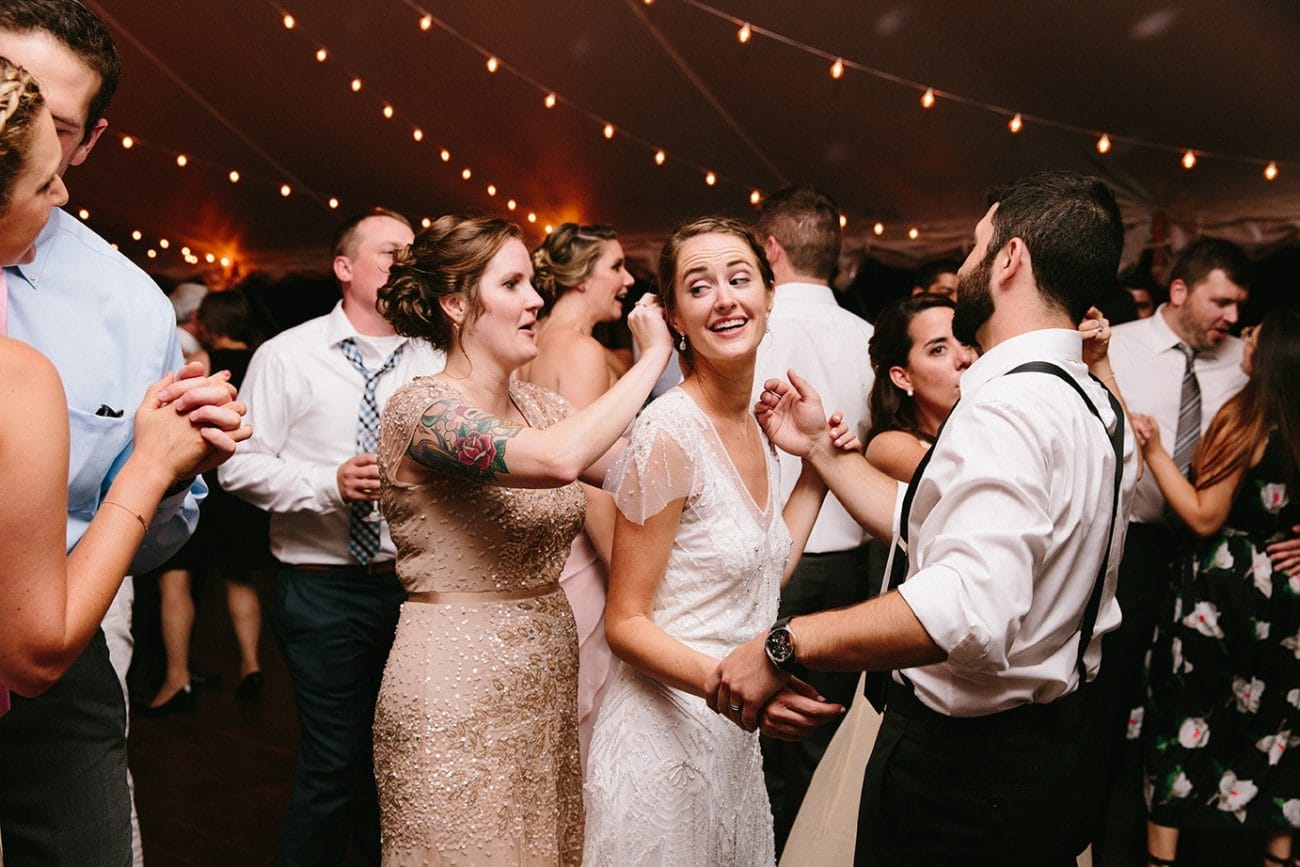 A documentary photograph of a bridesmaid fixing the brides hair while dancing during a Moraine Farm Wedding in Beverly, Massachusetts