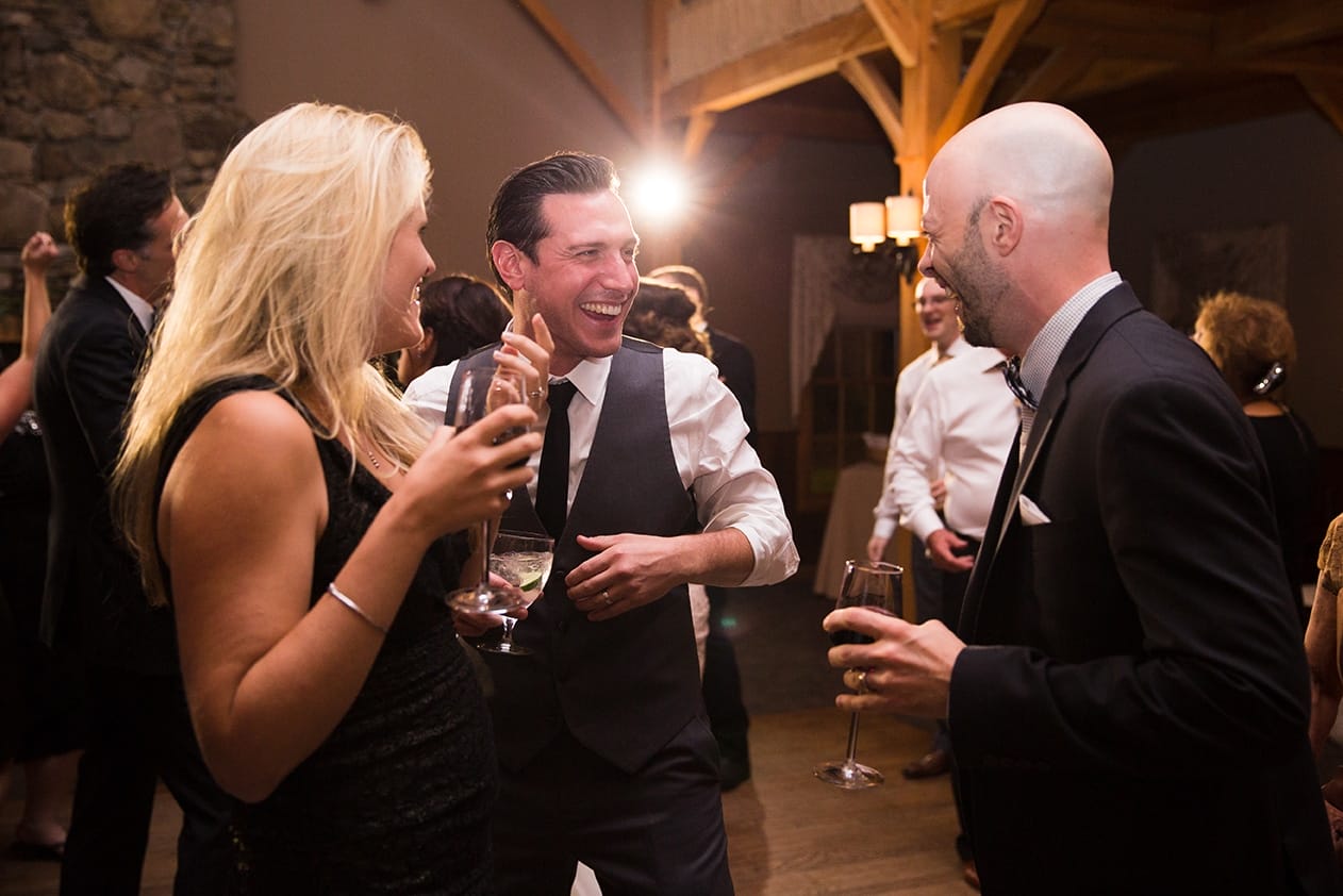 A documentary photograph of a groom laughing with his guests during a Harrington Farm Wedding in Princeton, Massachusetts