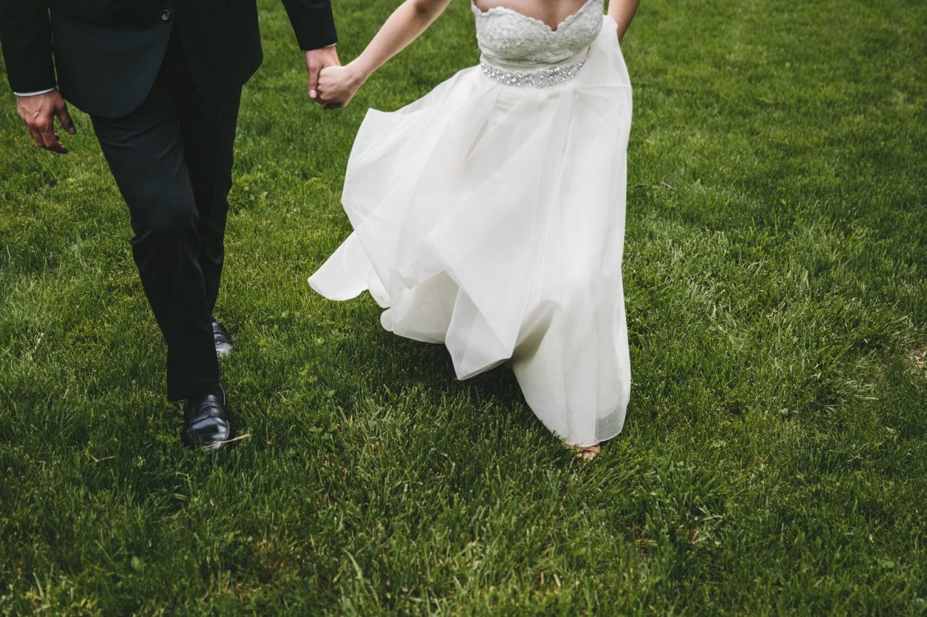 A documentary photograph of a bride and groom walking in the grass together before their Tower Hill Wedding in Boylston, Massachusetts