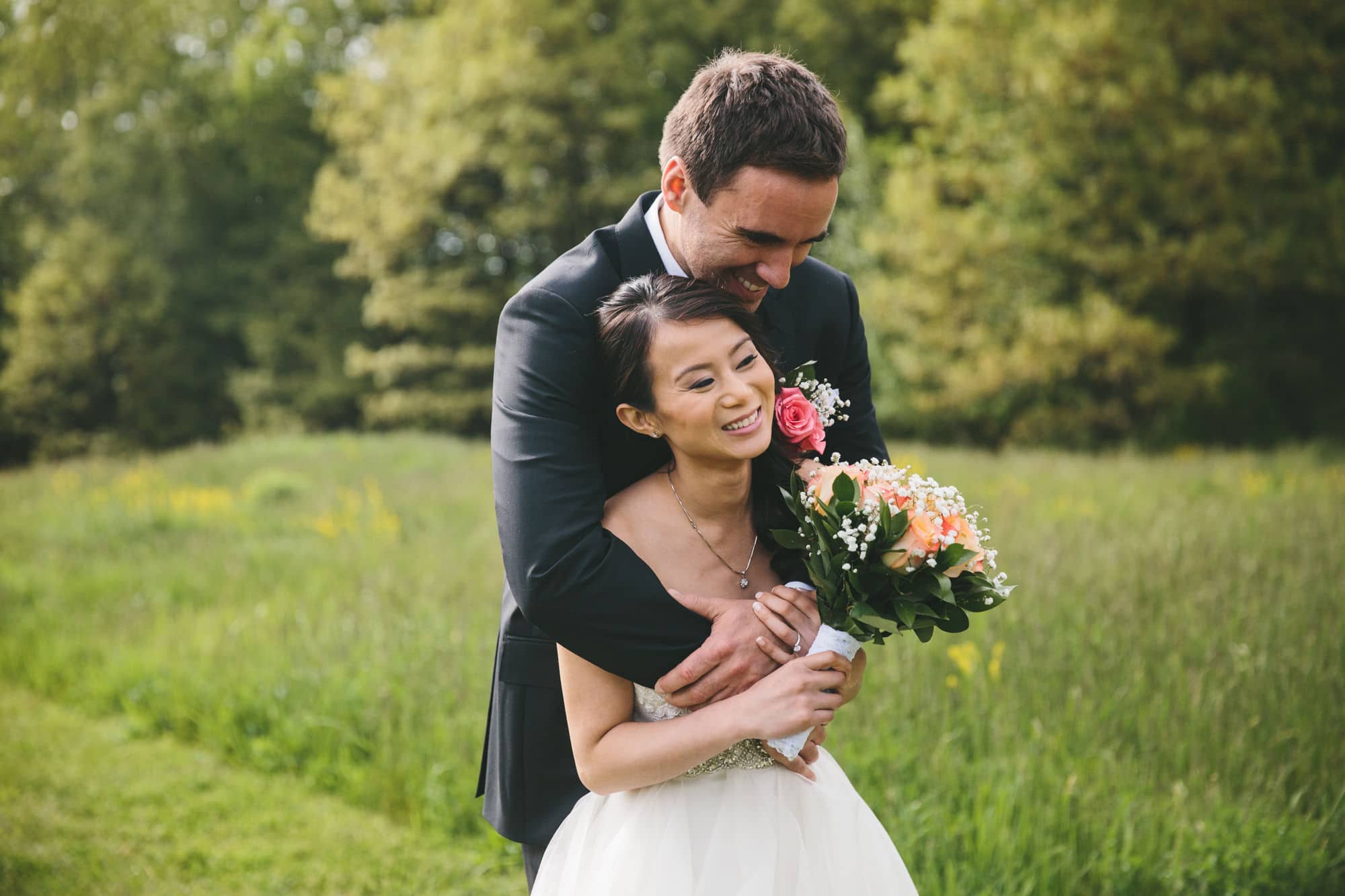 A documentary photograph of a bride and groom hugging and laughing before their Tower Hill Wedding in Boylston, Massachusetts