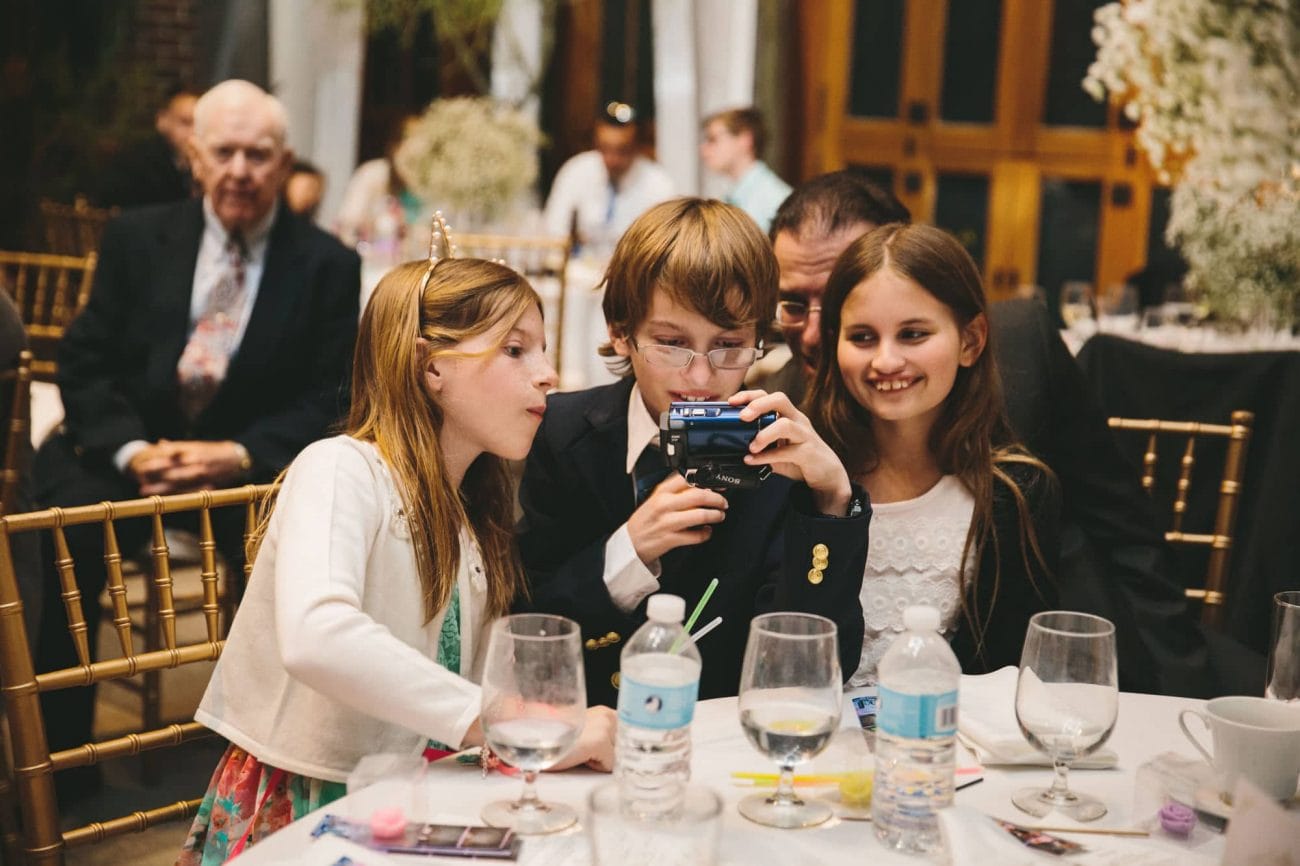A documentary photograph of kids looking at the photographs during a tower hill wedding reception in Boylston, Massachusetts