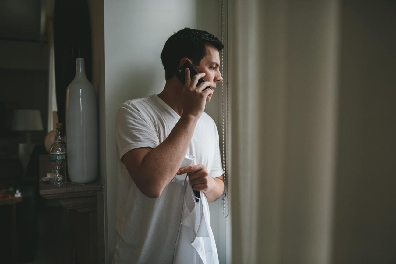 A documentary photograph of groom talking on the phone before his State Room Wedding