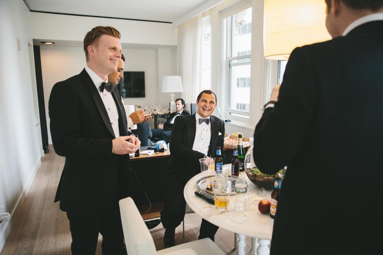 A documentary photograph of groomsmen laughing at the Ames Hotel before a State Room Wedding