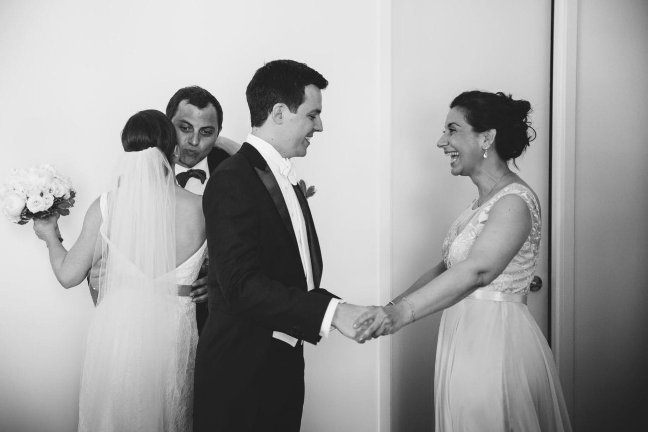 A documentary photograph of a bride and groom hugging their family before their State Room Wedding