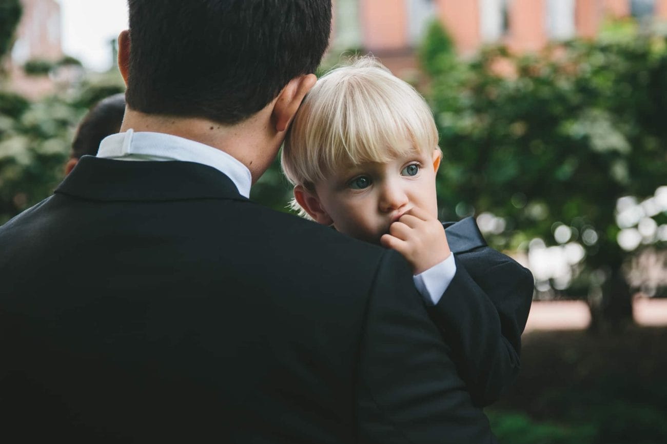 A documentary photograph of the groom holding the ring bearer before a State Room Wedding in Boston, Massachusetts