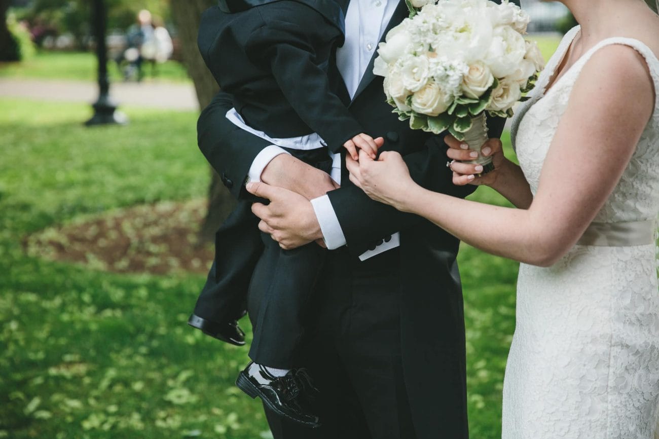 A documentary photograph of the bride and groom holding the ring bearer before their State Room Wedding in Boston, Massachusetts