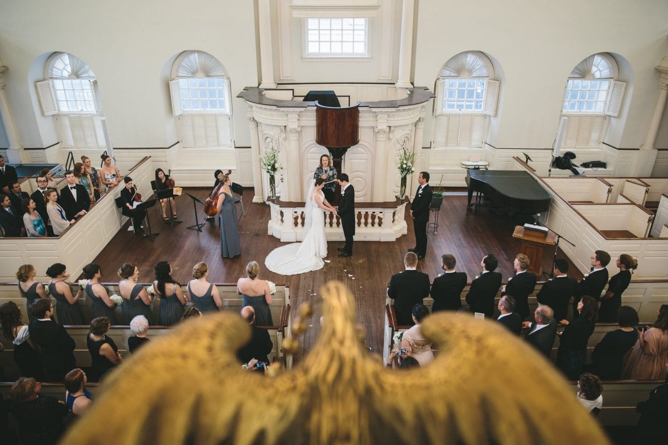 A documentary photograph of a bride and groom saying their vows during an old south meeting house wedding ceremony