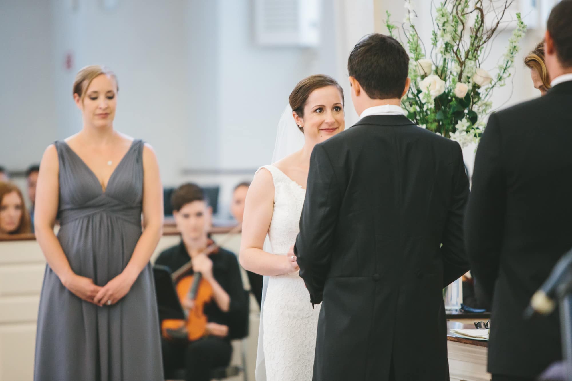 A documentary photograph of a bride smiling at her groom during an old south meeting house wedding ceremony in Boston, Massachusetts