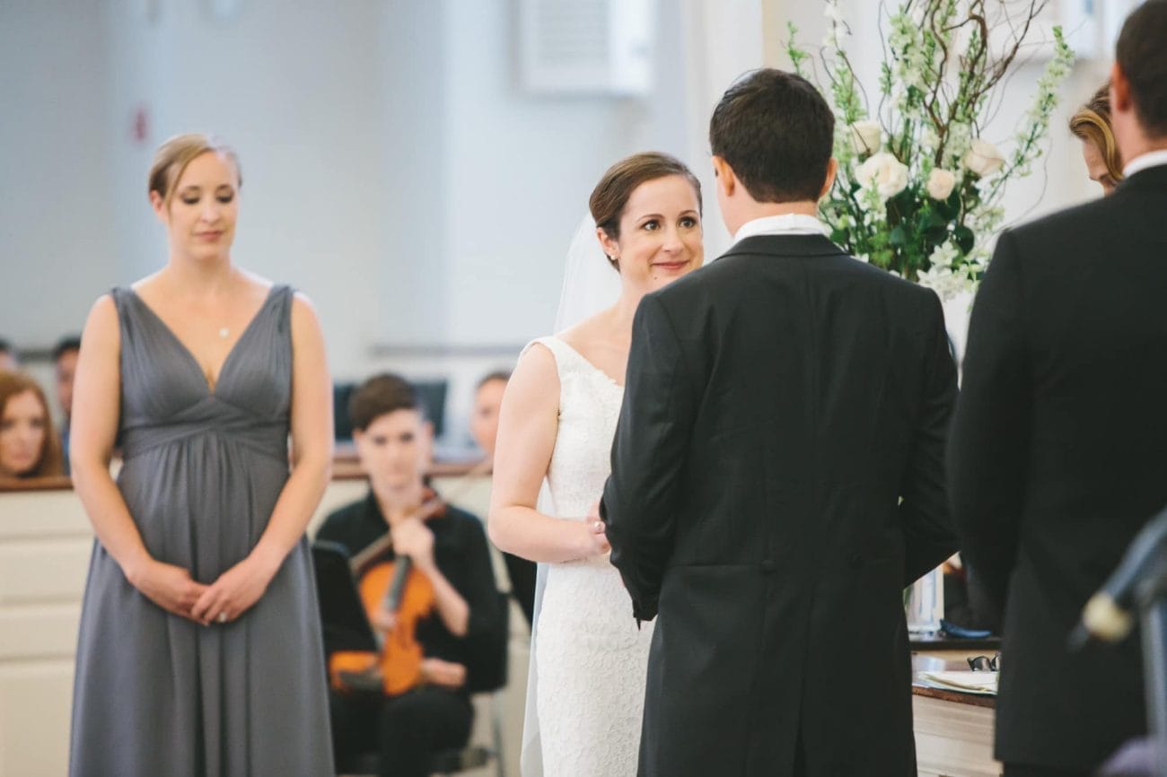A documentary photograph of a bride smiling at her groom during an old south meeting house wedding ceremony in Boston, Massachusetts