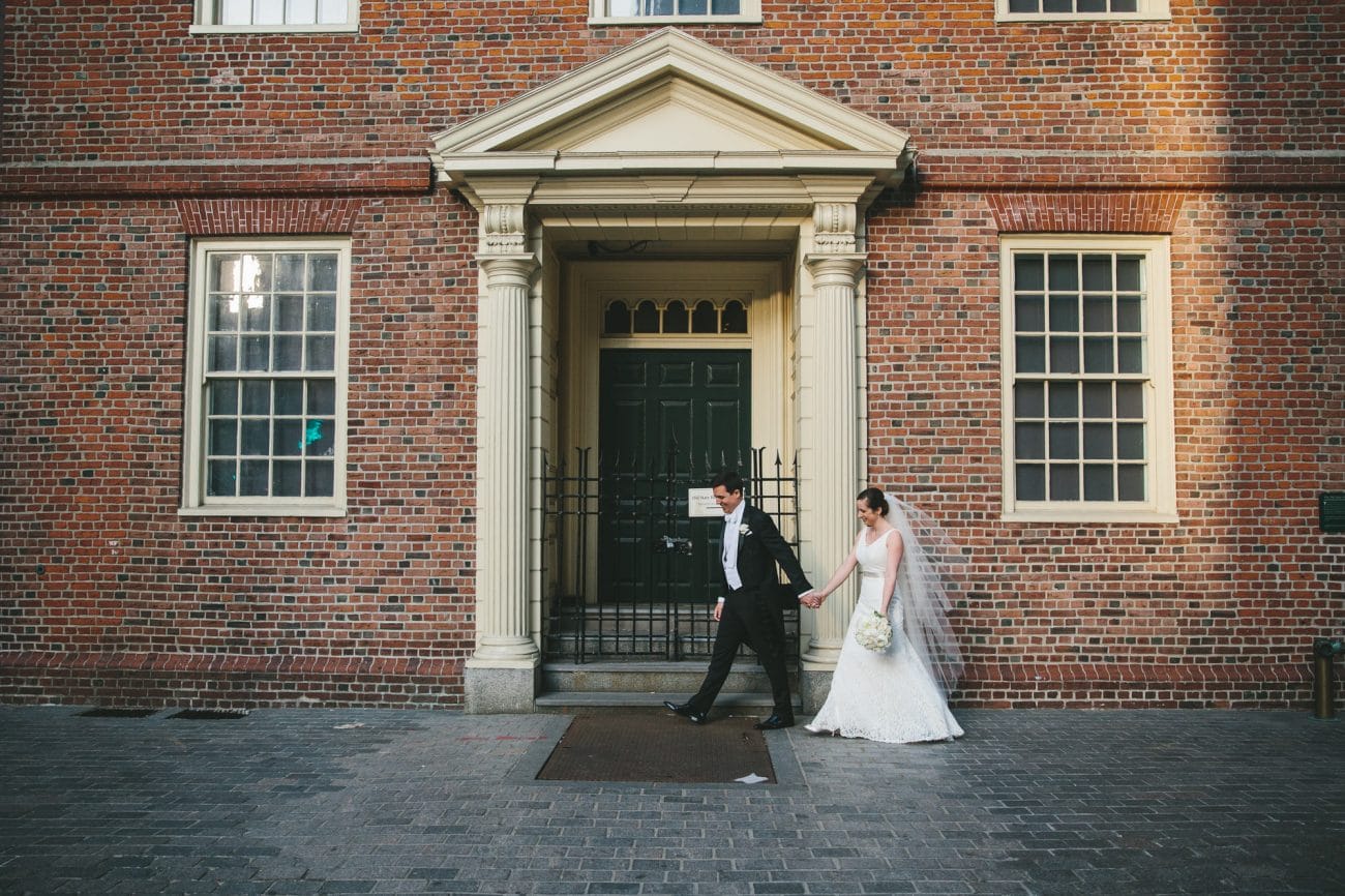 A documentary photograph of a bride and groom walking to their State Room Wedding Reception