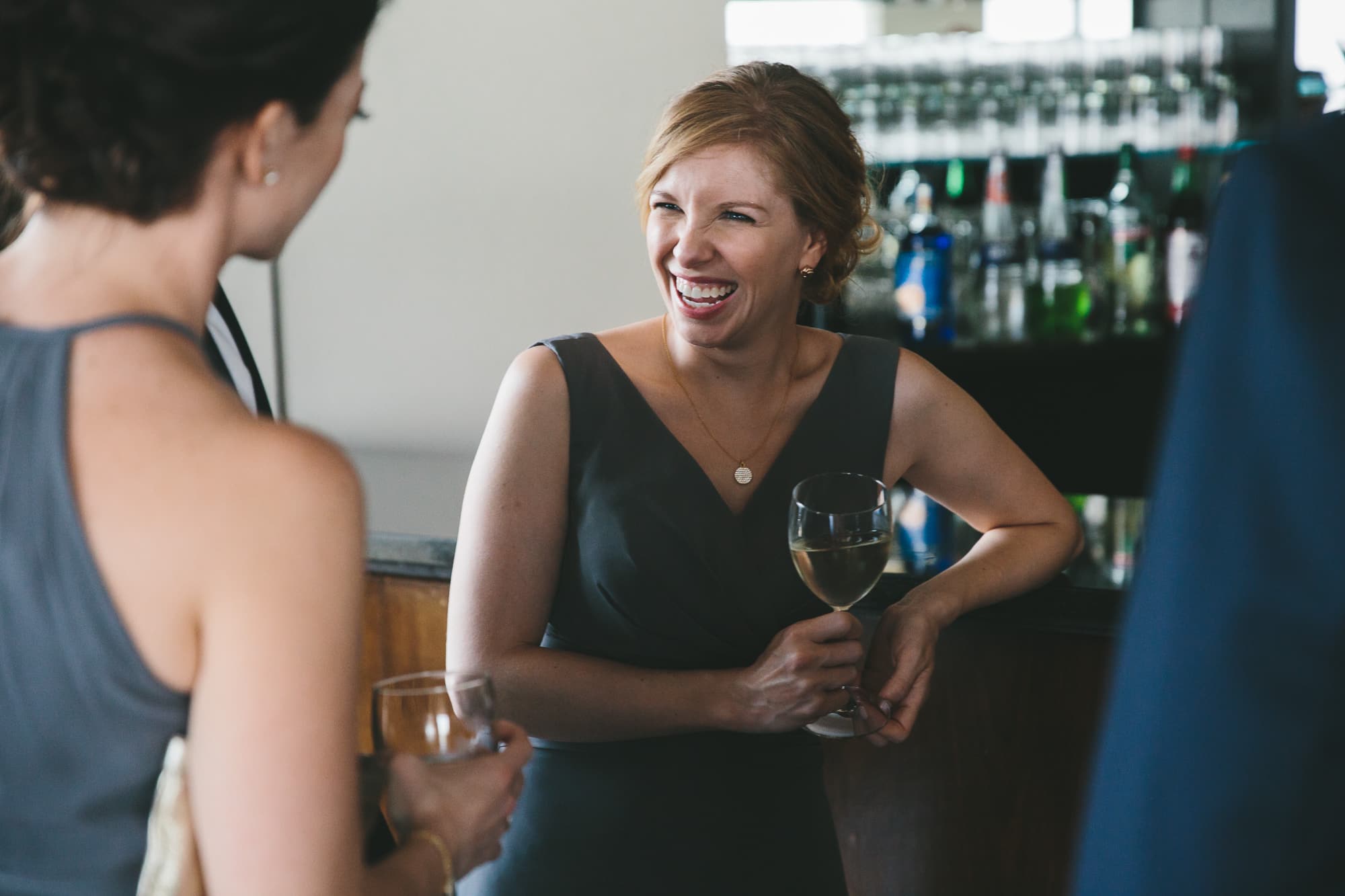 A documentary photograph of bridesmaids talking during a state room wedding reception