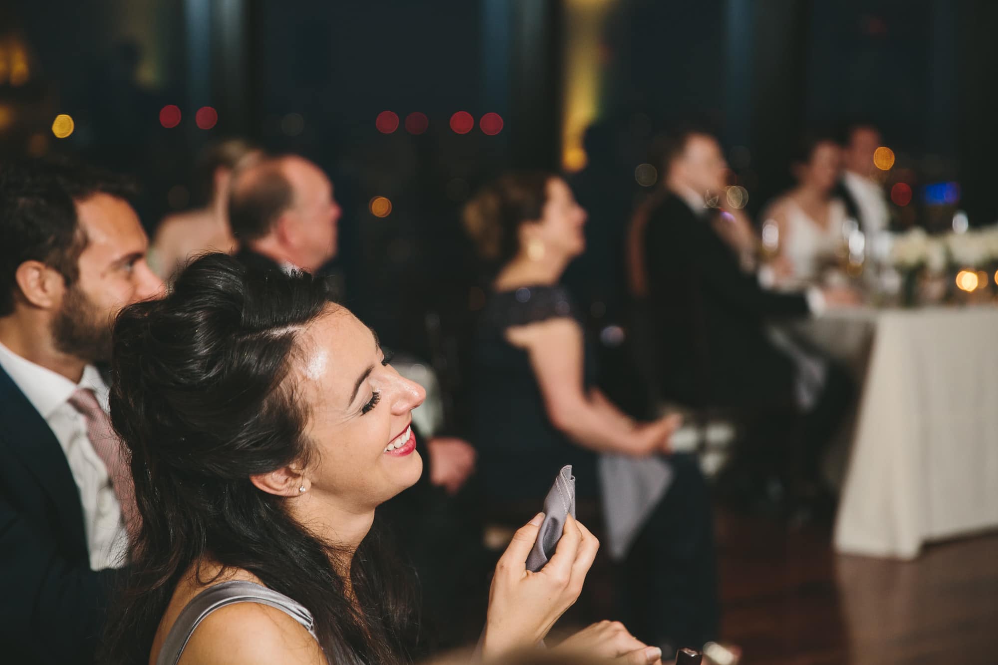 A documentary photograph of guests laughing during the speeches at a State Room Wedding reception