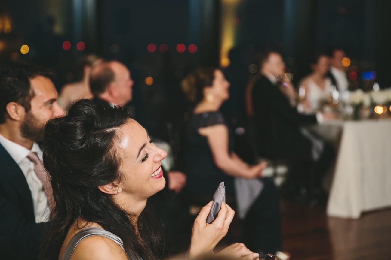A documentary photograph of guests laughing during the speeches at a State Room Wedding reception