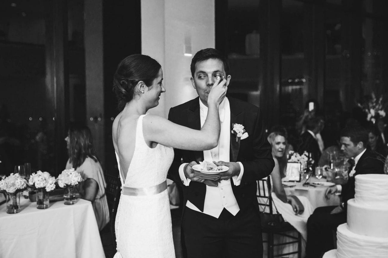 A documentary photograph of a bride feeding her groom cake during a state room wedding reception