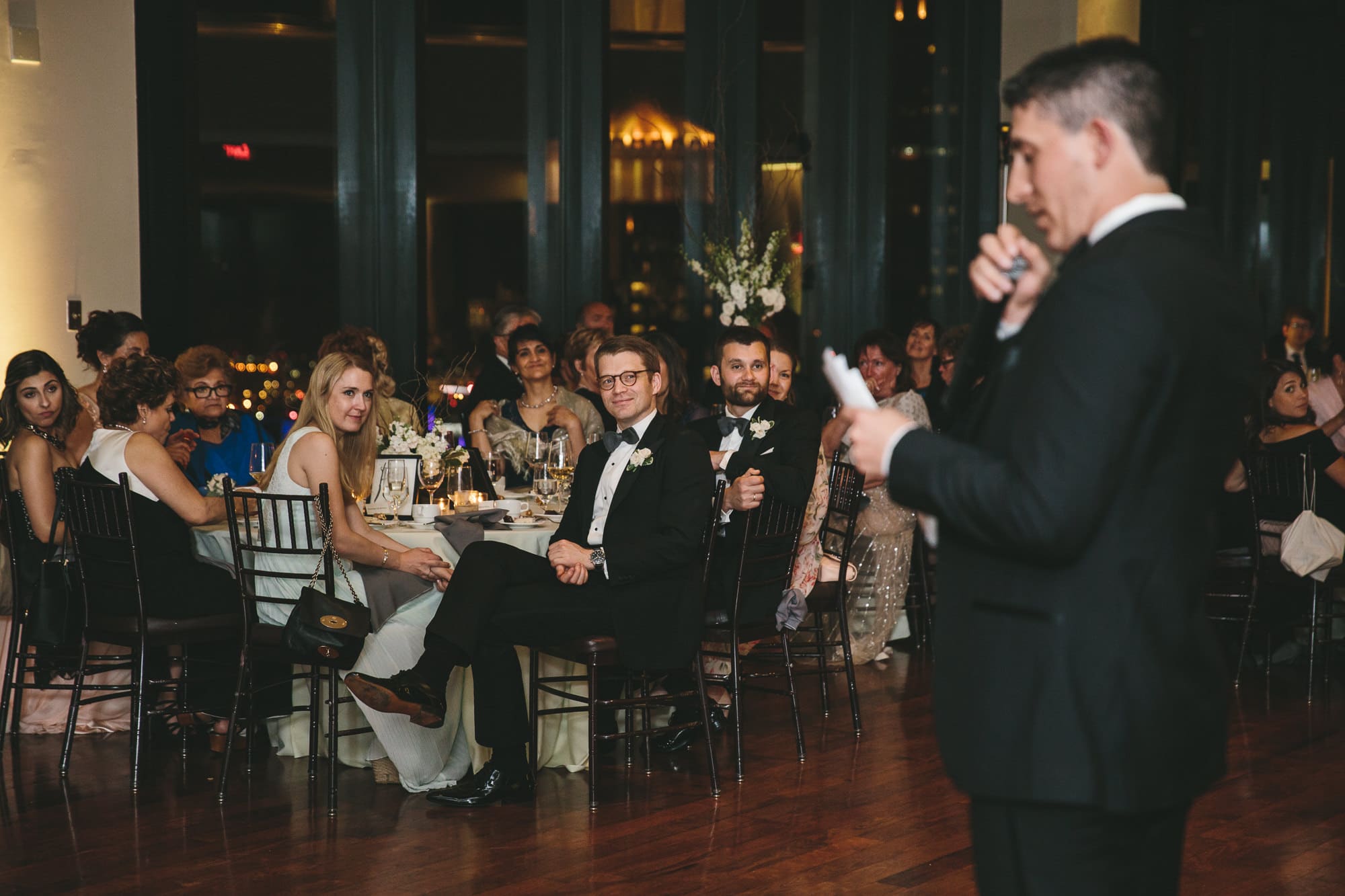 A documentary photograph of the wedding speeches during a state room wedding reception