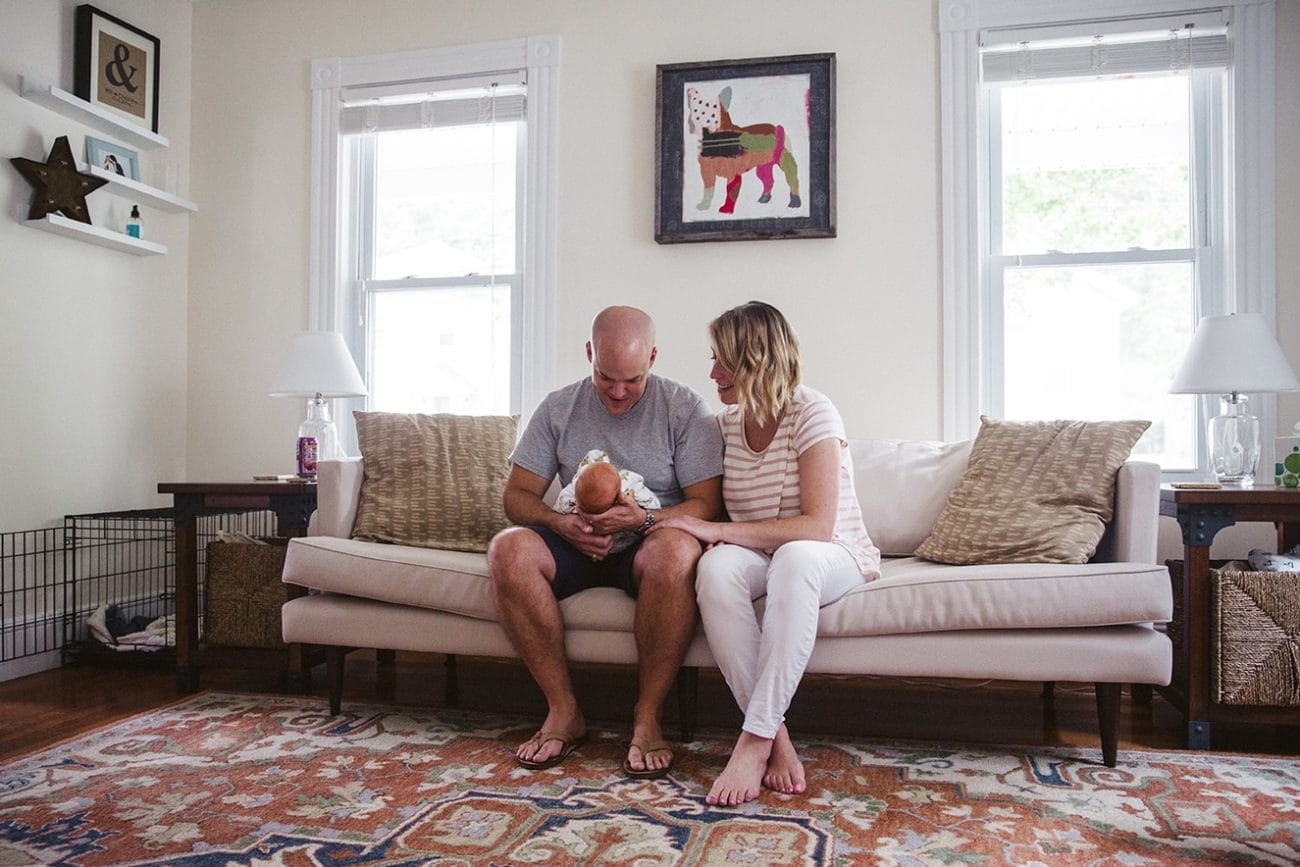 A documentary photograph of new parents admiring their newborn baby girl during an in home lifestyle newborn session in Boston, Massachusetts