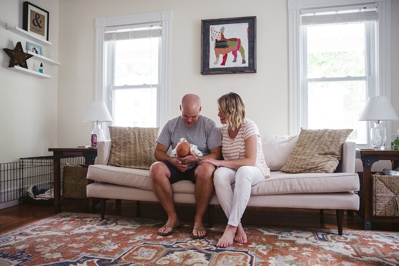 A documentary photograph of new parents admiring their newborn baby girl during an in home lifestyle newborn session in Boston, Massachusetts