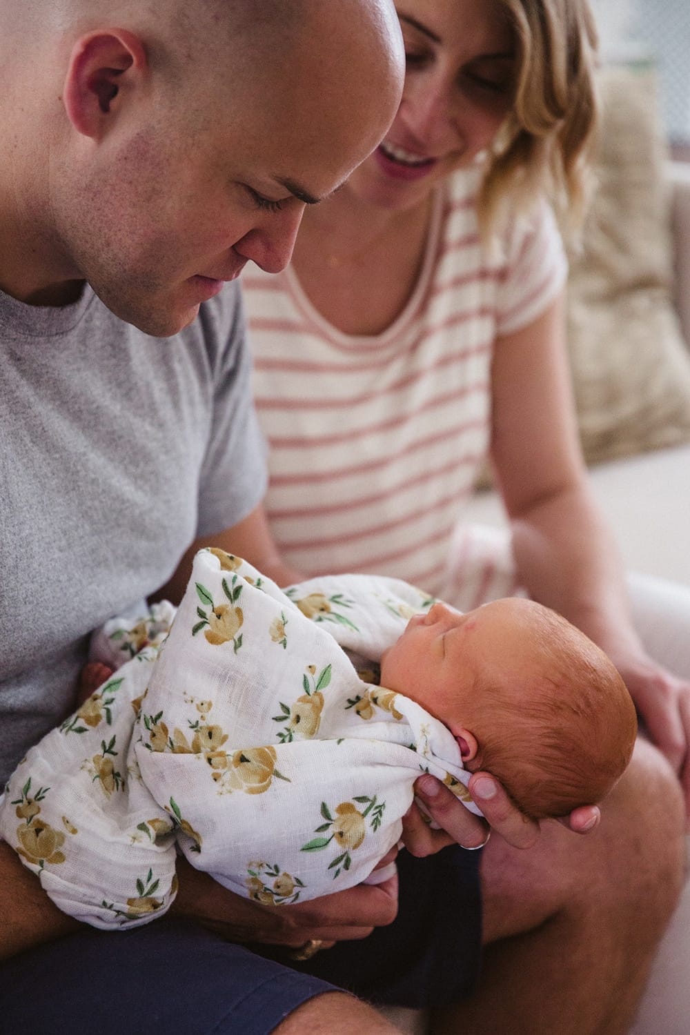 A documentary portrait of new parents admiring their newborn baby girl during their in home lifestyle newborn session in Boston, Massachusetts